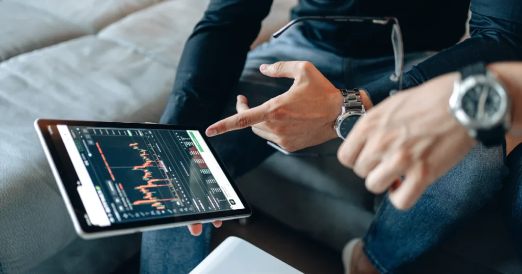 Traders reviewing live crypto chart on tablet reflecting Crypto Compliance